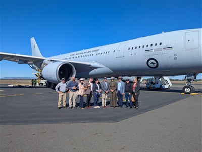 Group of people standing in front of a Royal Australian Air Force aircraft on an airfield.