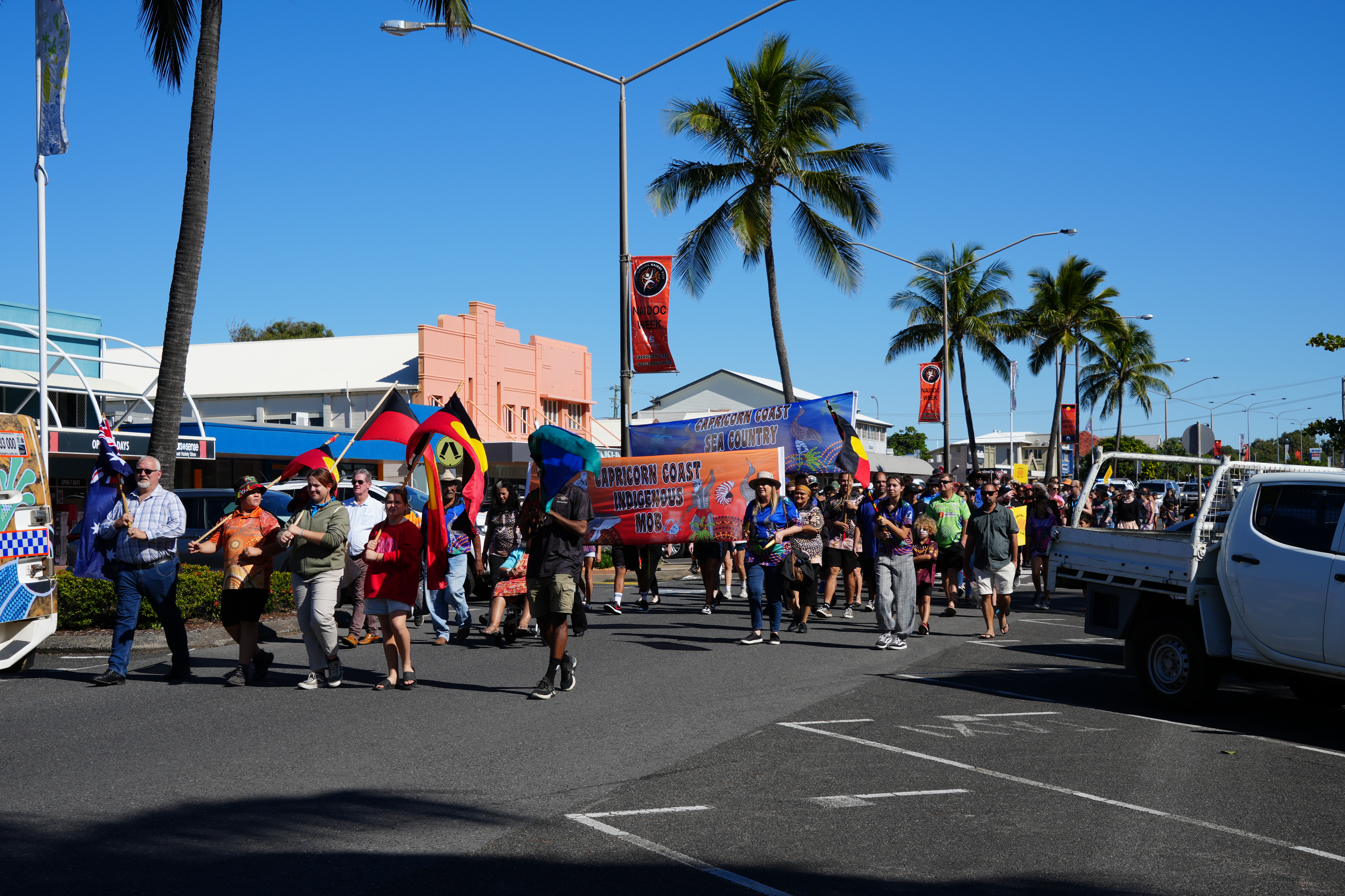 People marching in a street parade with banners reading “Capricorn Coast Sea Country” and “Capricorn Coast Indigenous Mob”.